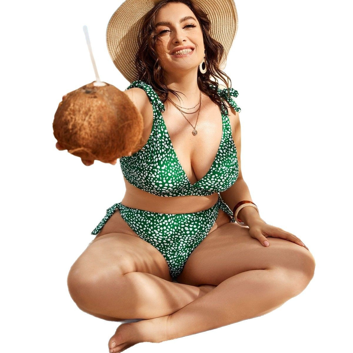 Woman in green bikini holding a coconut, posing playfully.