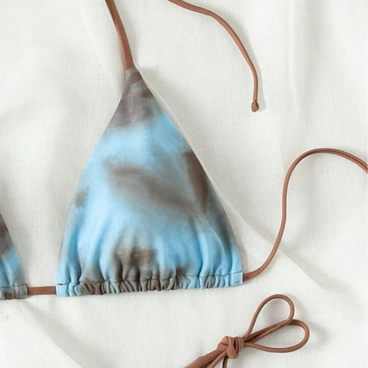 Tie-dye bikini top with brown straps on a white background