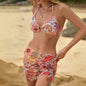 A woman wearing a multicolored swimsuit with a pleated tulle skirt standing on a beach