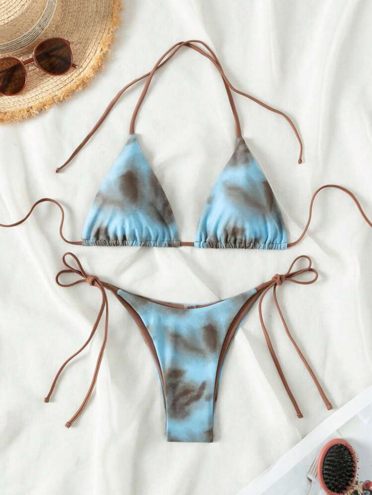 A two-piece swimsuit with blue tie-dye patterns and brown lacing details on a white background.