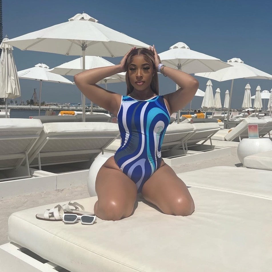 A woman sitting on a sun lounger wearing a blue and white striped swimsuit.