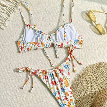Floral bikini set on a textured surface with a straw hat and sunglasses.