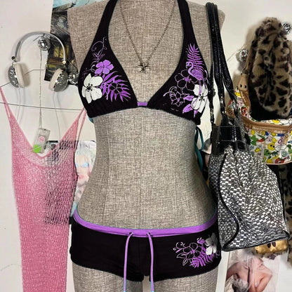A bikini suit on a mannequin featuring a sky blue top with a floral pattern and a solid black bottom, set against a backdrop with various accessories and clothing items.