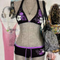 A bikini suit on a mannequin featuring a sky blue top with a floral pattern and a solid black bottom, set against a backdrop with various accessories and clothing items.