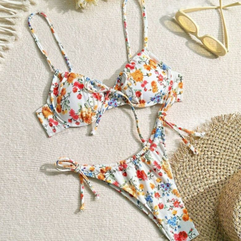 Floral bikini set on a textured surface with sunglasses.