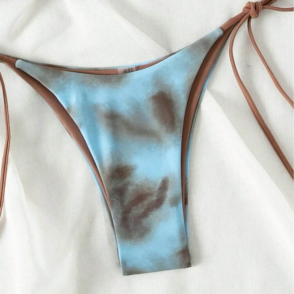 Blue and brown tie-dye bikini bottom with side ties on a white background.