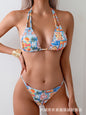 This image features a vibrant and colorful printed bikini swimsuit. The bikini top is adorned with a lively floral and tropical print, reminiscent of a beach or holiday destination.