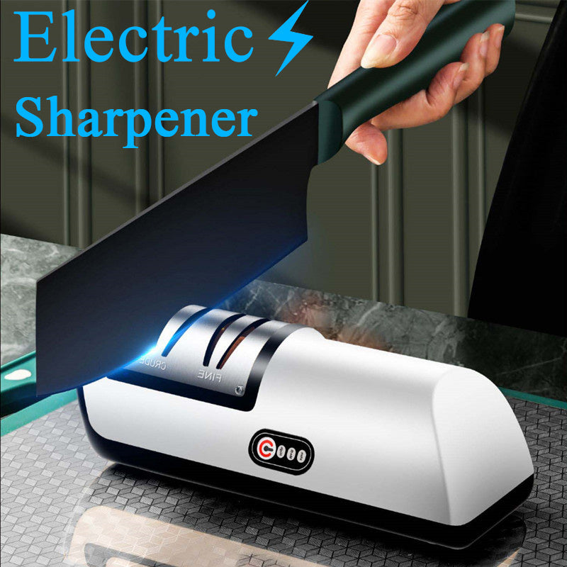 An electric knife sharpener in white and black colors, with a knife being sharpened by it, against a kitchen background.