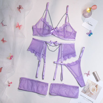 A woman modeling a pink lingerie set which includes a bra, panties, and garter straps.