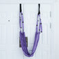 A person using a purple yoga inversion and stretching strap to assist with a yoga pose, hanging from a door frame.