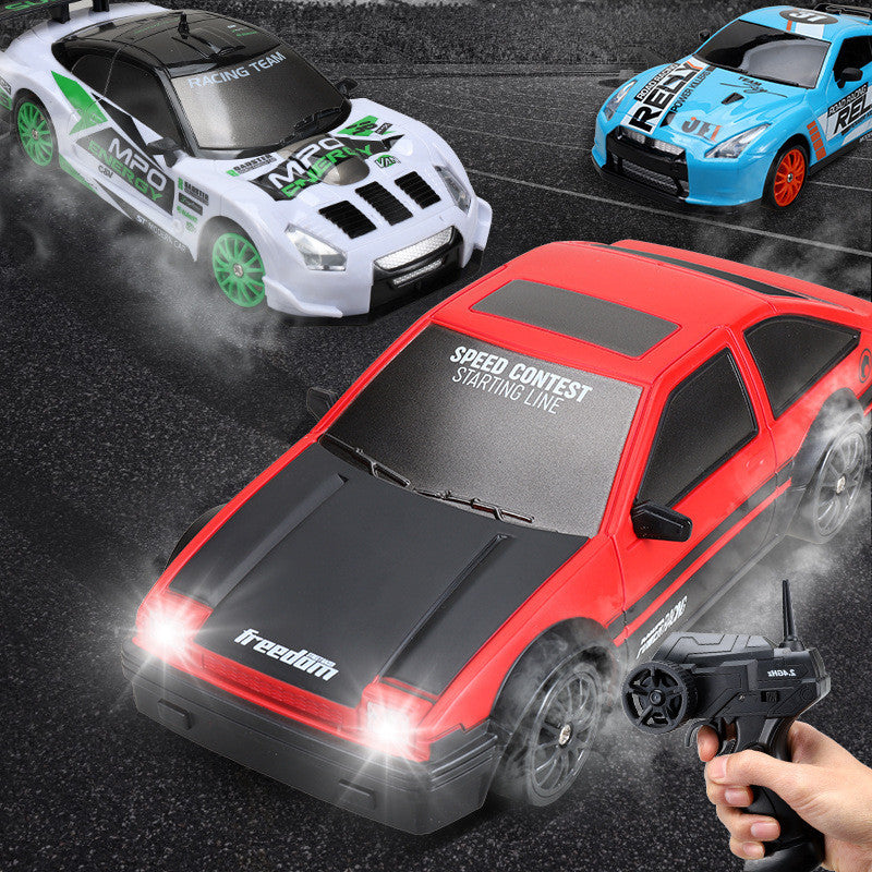 A hand holding a remote control operating a red and black RC drift car toy, with other cars in the background.