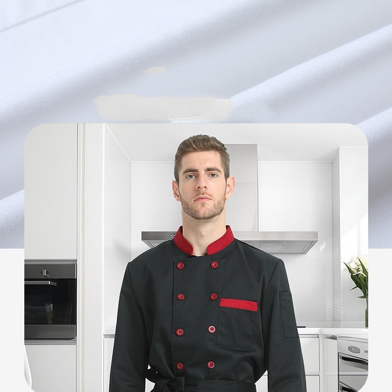 A man standing in a kitchen wearing a black chef coat with red buttons and trim.