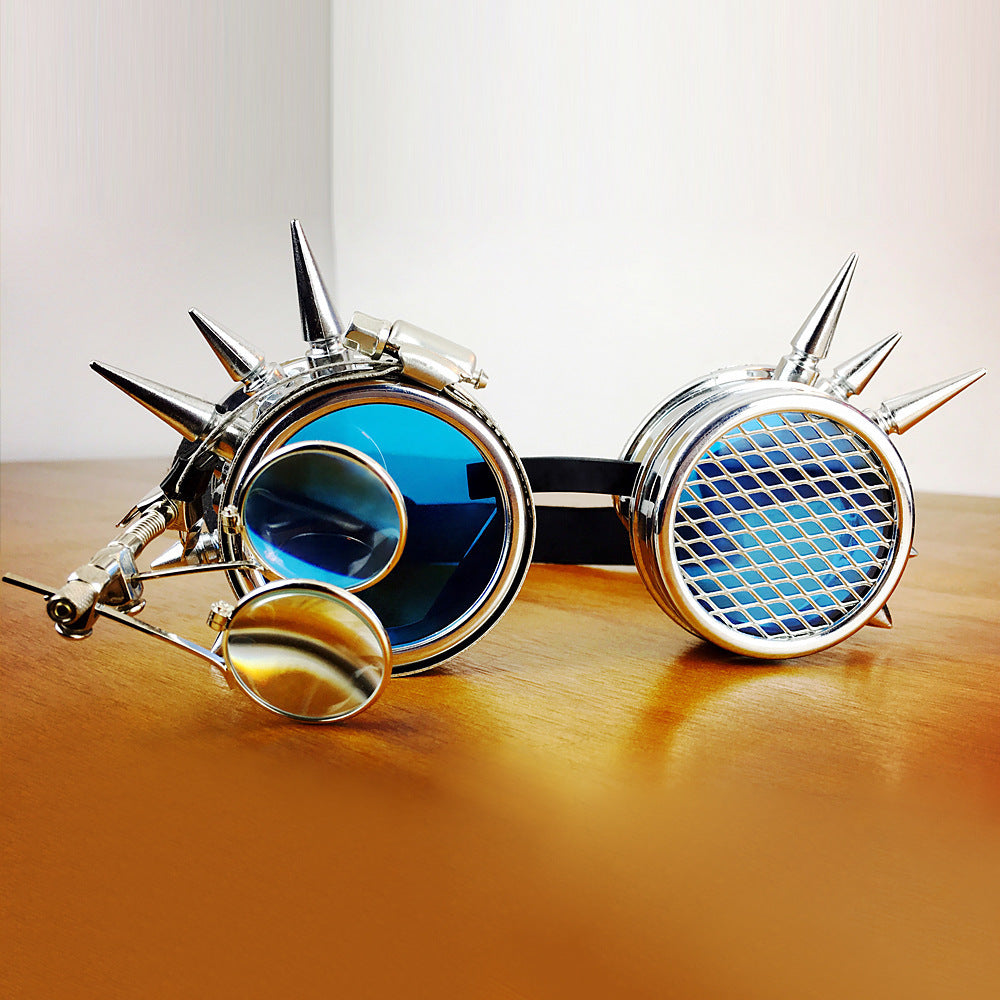 A pair of blue tinted goggles with silver metal frames and spike decorations on the sides.