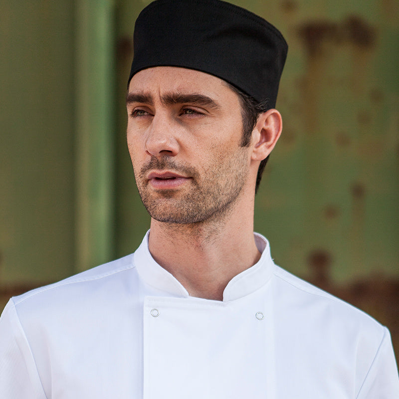A person wearing a white chef uniform and a black working hat.
