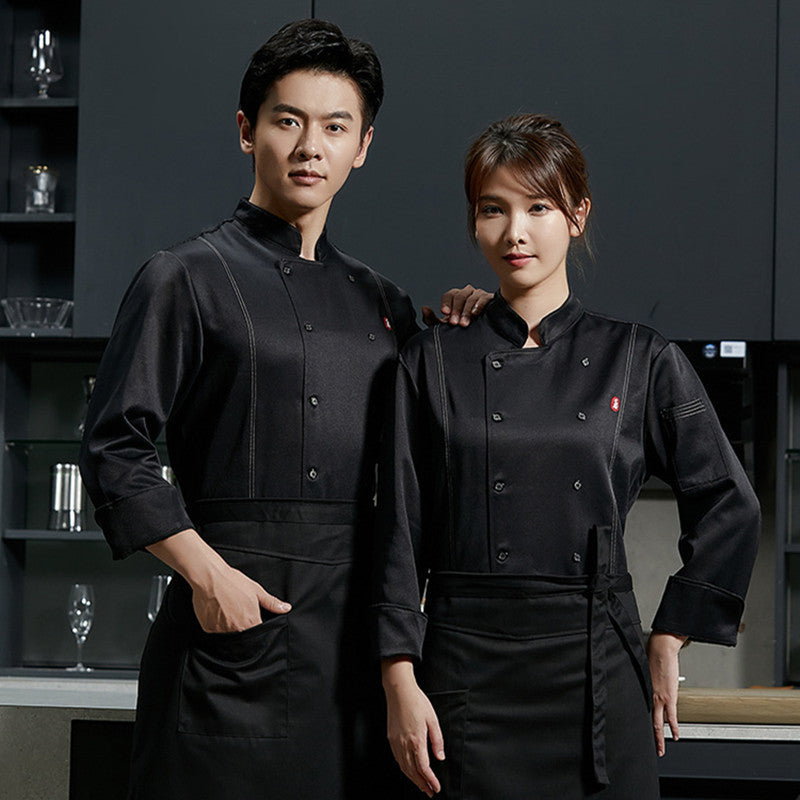 Two adults, one male and one female, wearing long sleeve black chef overalls with button-up front and apron pockets.