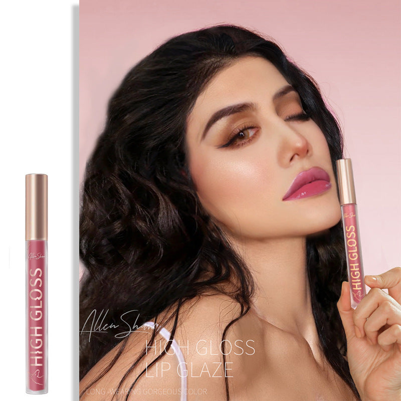 Woman with closed eyes holding a lip gloss against a pink background