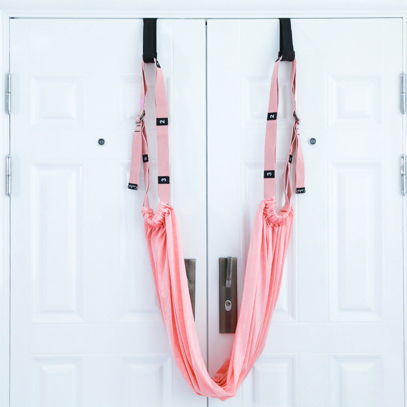 A person using a purple yoga inversion and stretching strap to assist with a yoga pose, hanging from a door frame.