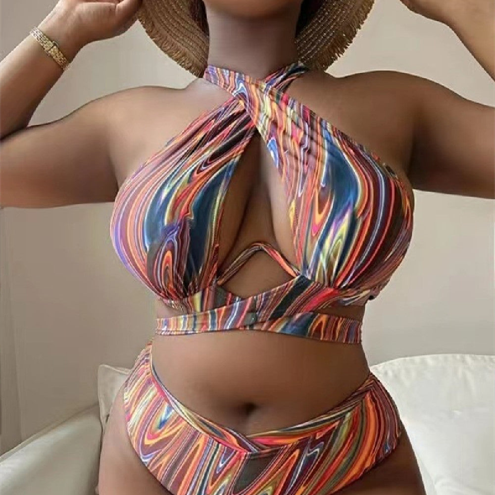 A woman wearing a high-waisted, multicolored, floral bikini swimsuit with a halter neck.