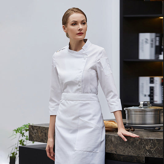 A woman wearing a long sleeve white chef coat with a round neckline, with the coat hanging to her waist and a button-up front.
