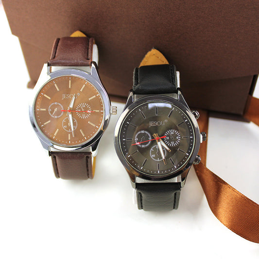 Two men's watches with leather straps and multicolored dials, displayed alongside a brown wallet and a ribbon, suggestive of a gift set.