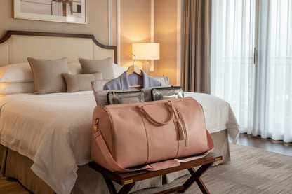Pink travel bag with a hanger and garment inside, on a white background